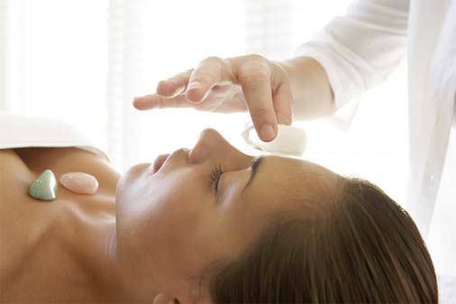 Therapist placing quartz crystal on woman's forehead